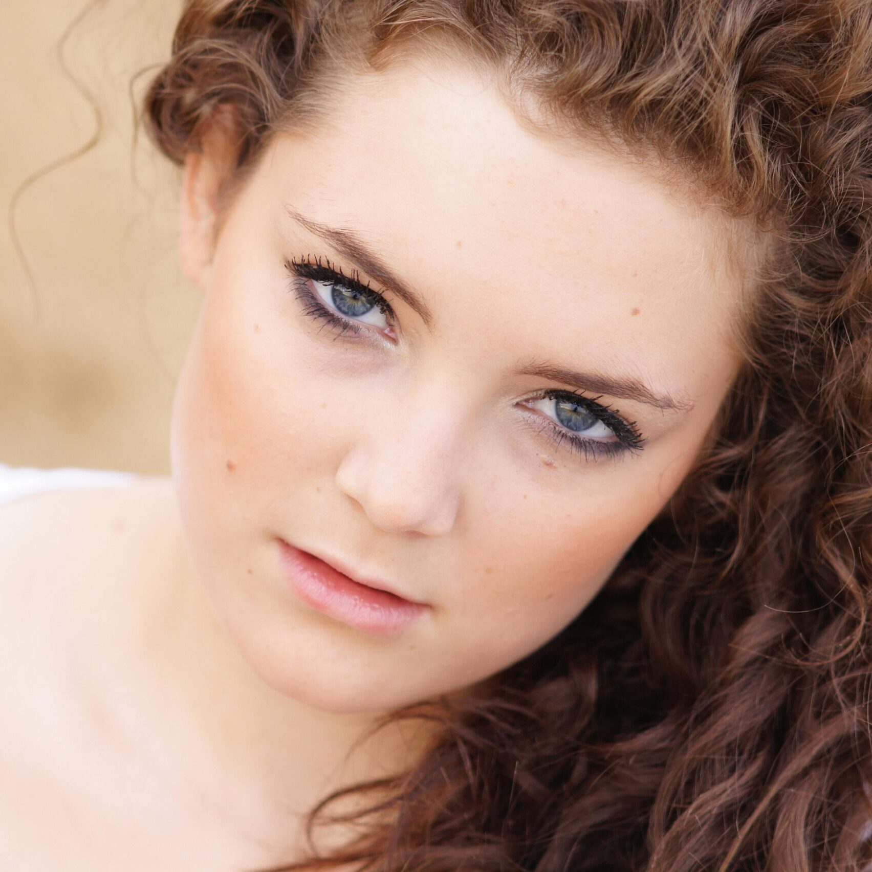 Close-up portrait of a young woman with curly hair, showcasing natural beauty and elegance.